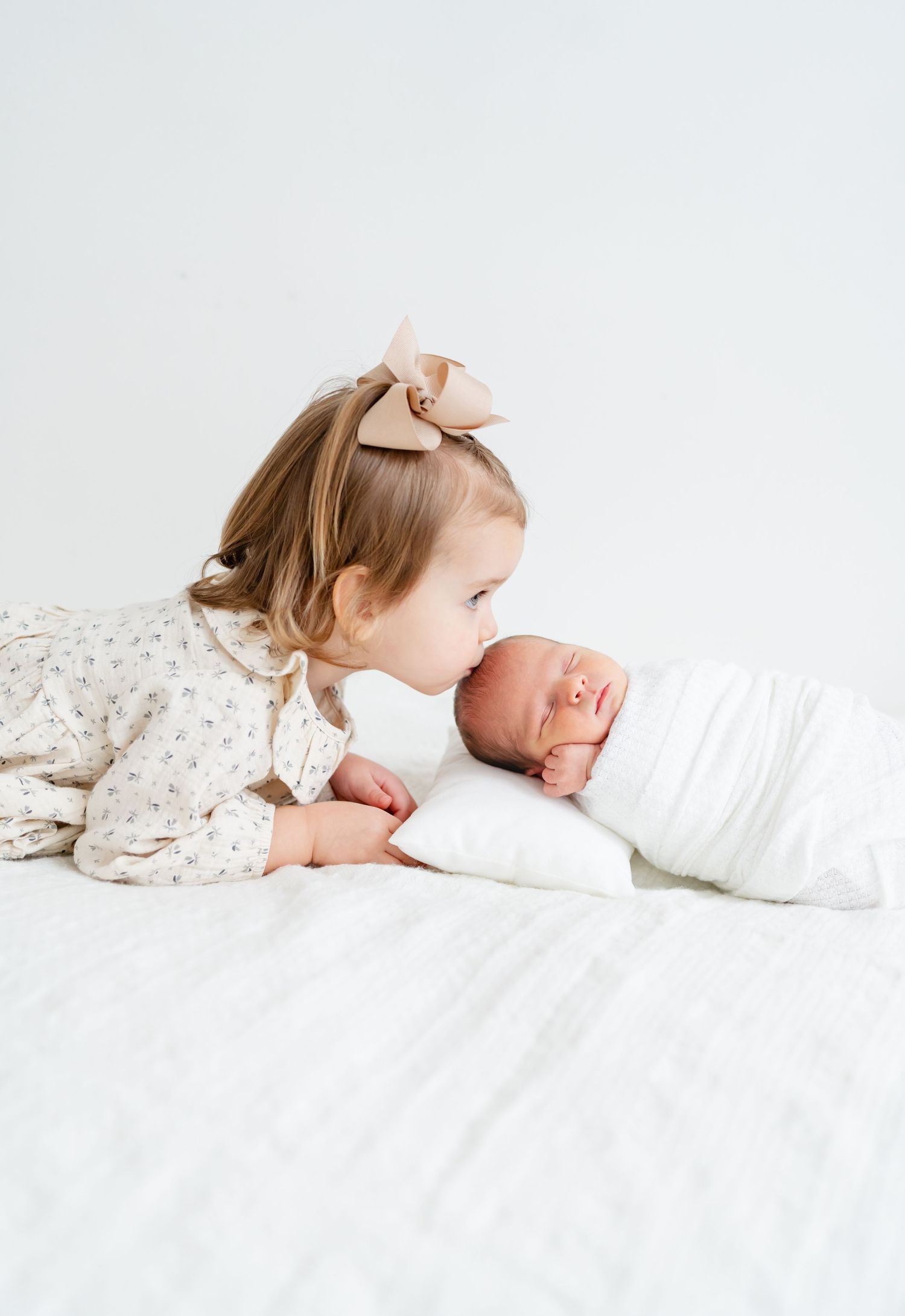 Sleeping newborn wrapped in pink swaddle on white blanket in woven basket.