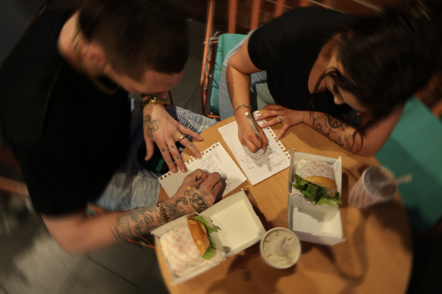 Overhead view of people sharing a casual meal together at a wooden table. Date night at Bettys Burgers.