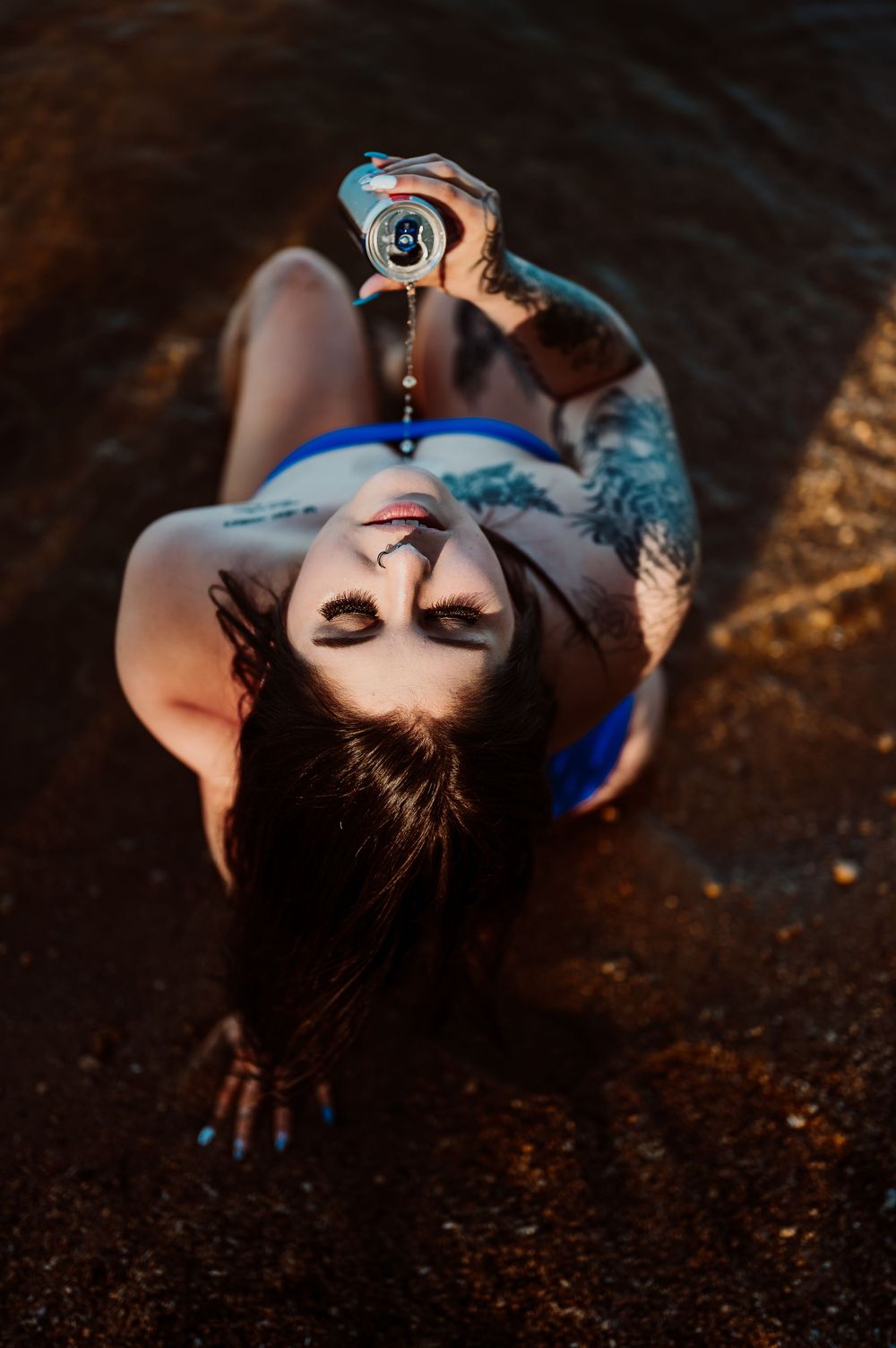 Artistic portrait shot of woman lying on dark ground with dramatic lighting.