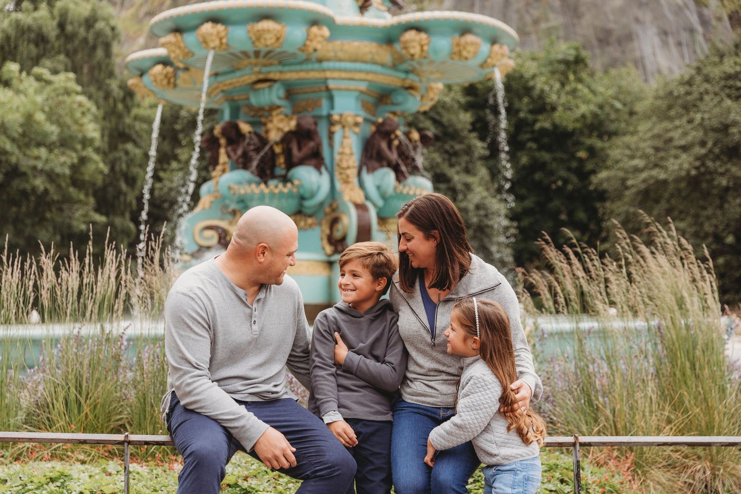 A family sharing a tender moment on a bench near a vintage carousel.