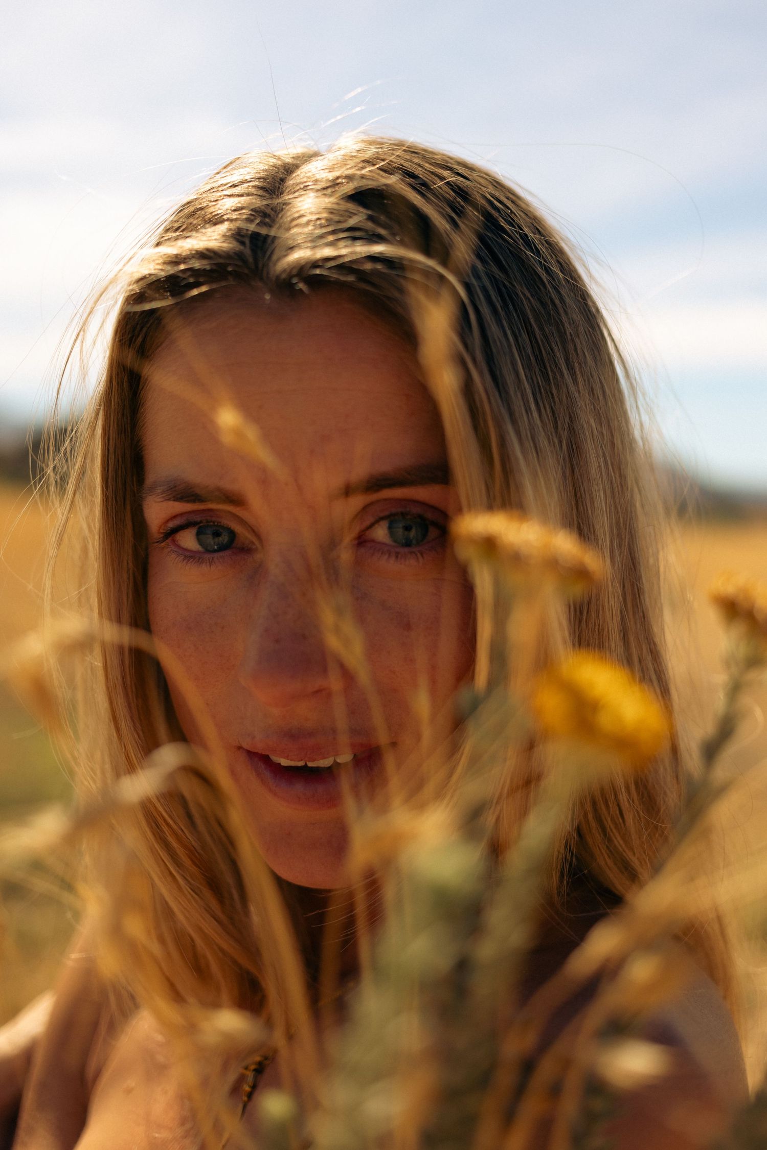 Portrait in golden wildflower field with soft natural lighting.