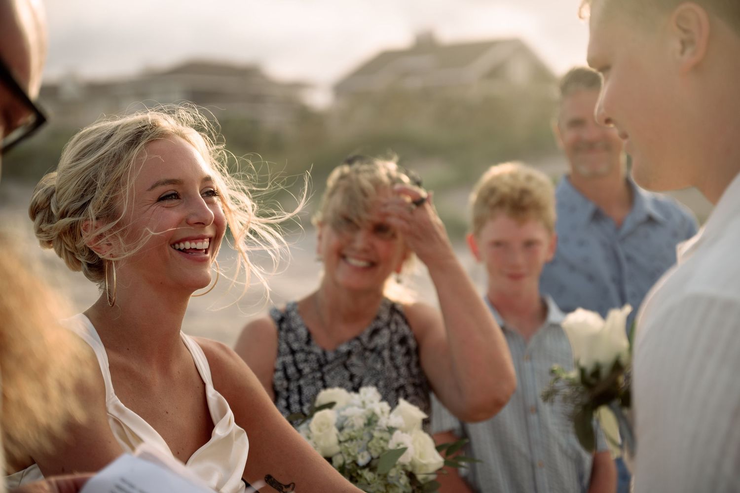 A candid moment of joy and laughter during a casual beach wedding celebration.