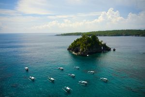 Aerial view of boats anchored near tropical island in crystal clear turquoise waters.