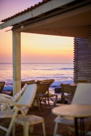 Beachfront patio with lounge chairs overlooking ocean at sunset.