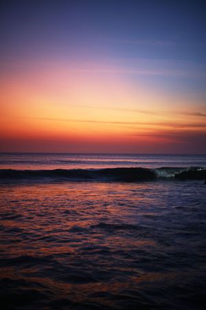 Vibrant sunset over ocean waves with orange and purple sky.