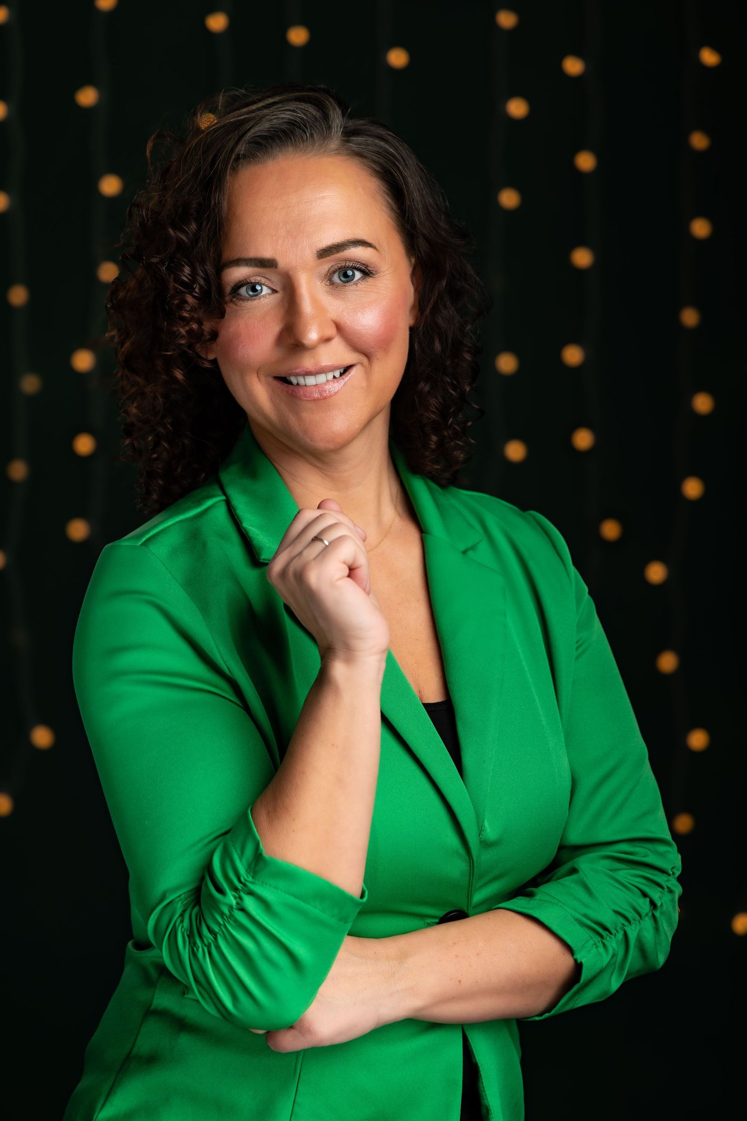Professional studio portrait with person wearing green cardigan against dark background.