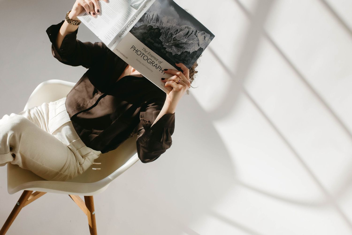 brand and event photographer in Stockholm sitting in a chair in studio holding a book in front of her face
