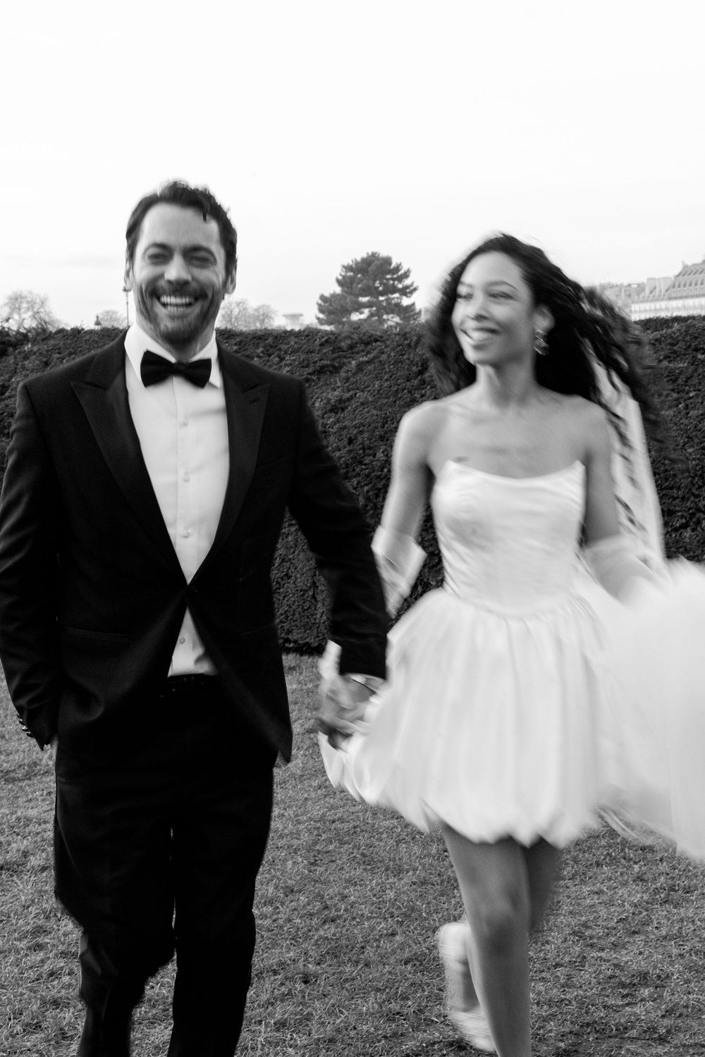 A joyful wedding couple runs playfully through a garden, captured in a series of black and white photographs.