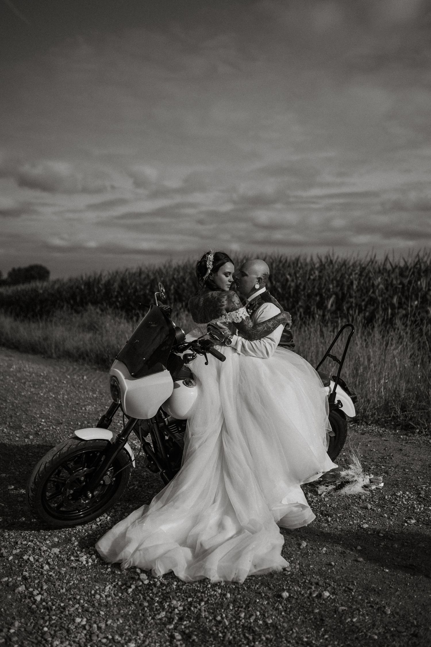 Photo of boho bride and groom sitting on motorcycle at a rustic barn wedding in southwest Michigan