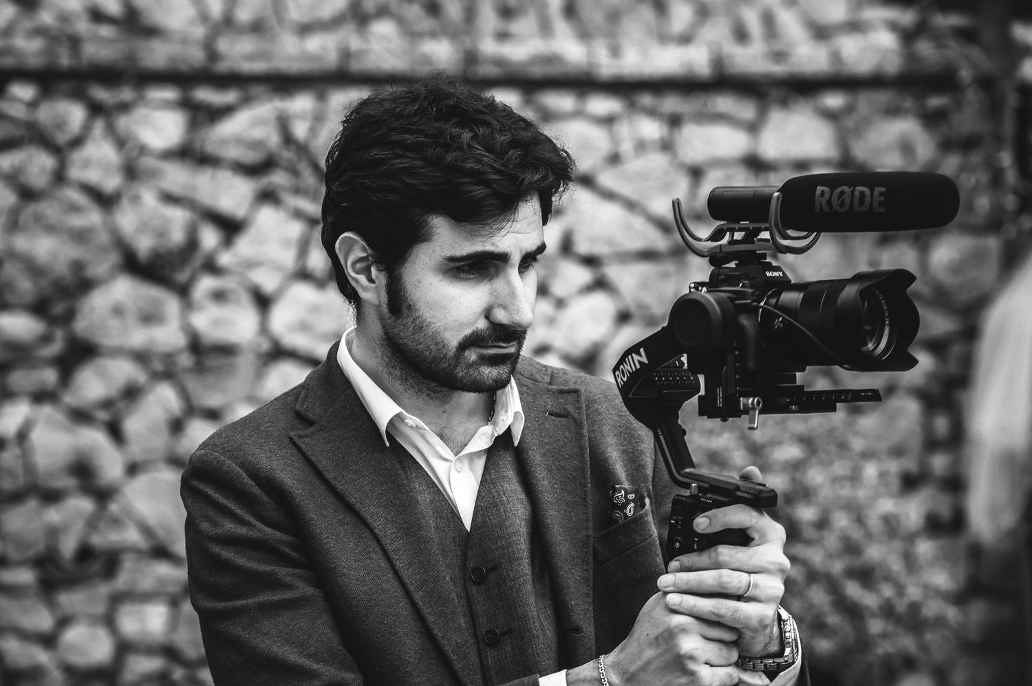 A videographer in formal attire operates a professional camera rig.