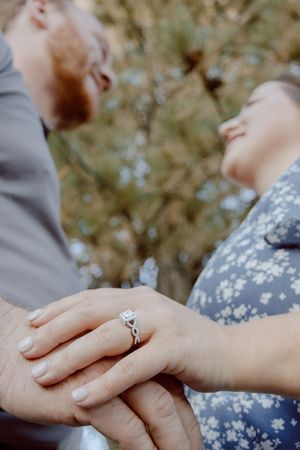 Close-up sequence showing hands with engagement ring joining together against a blurred natural background.