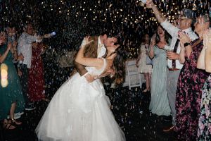Bride and groom share a romantic first dance surrounded by confetti and cheering guests at a wedding reception.