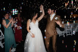 Bride and groom dancing joyfully at their wedding reception, surrounded by colorful bokeh lights and cheering guests.