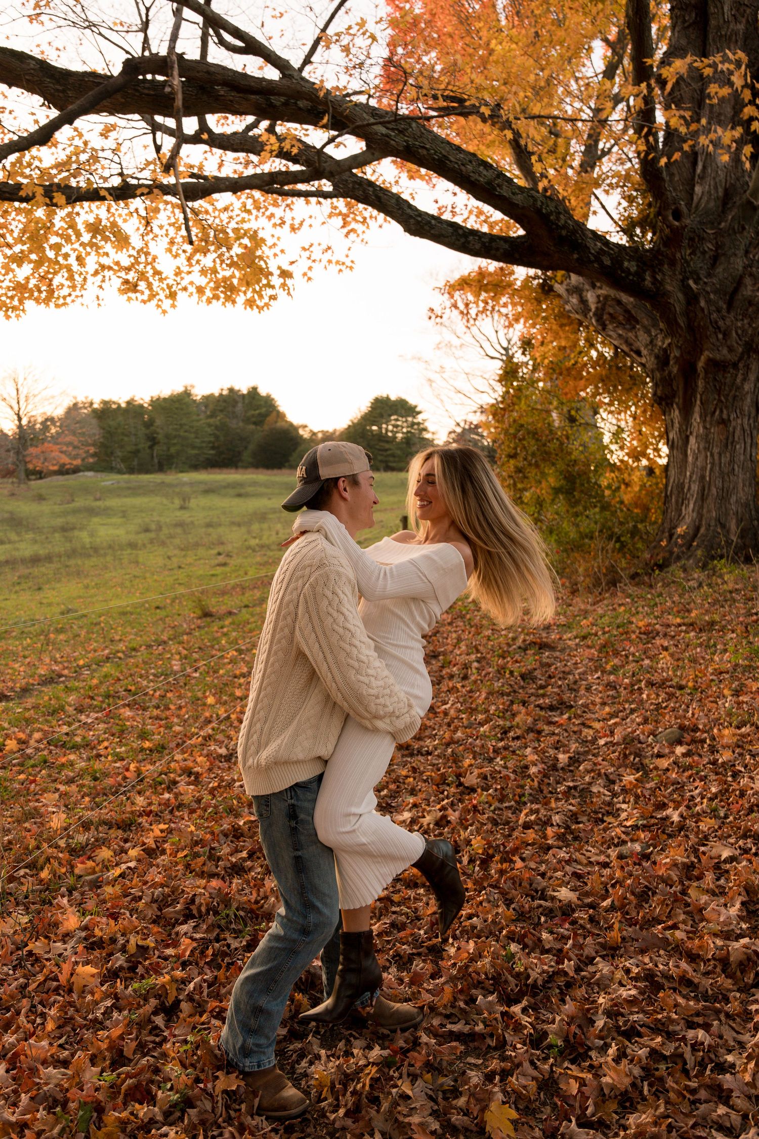 Boston engagement photo of couple kissing in Charlestown park during fall, dressed in stylish city-inspired outfits
