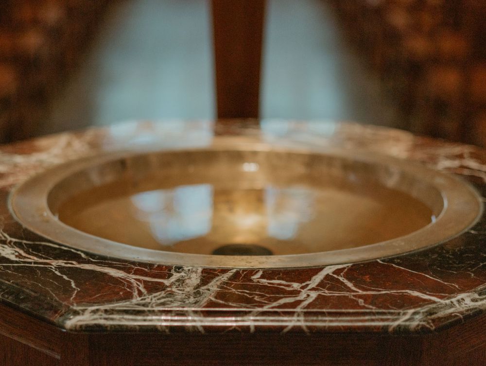 Close-up of ornate gold baptismal font with marble details in church setting.