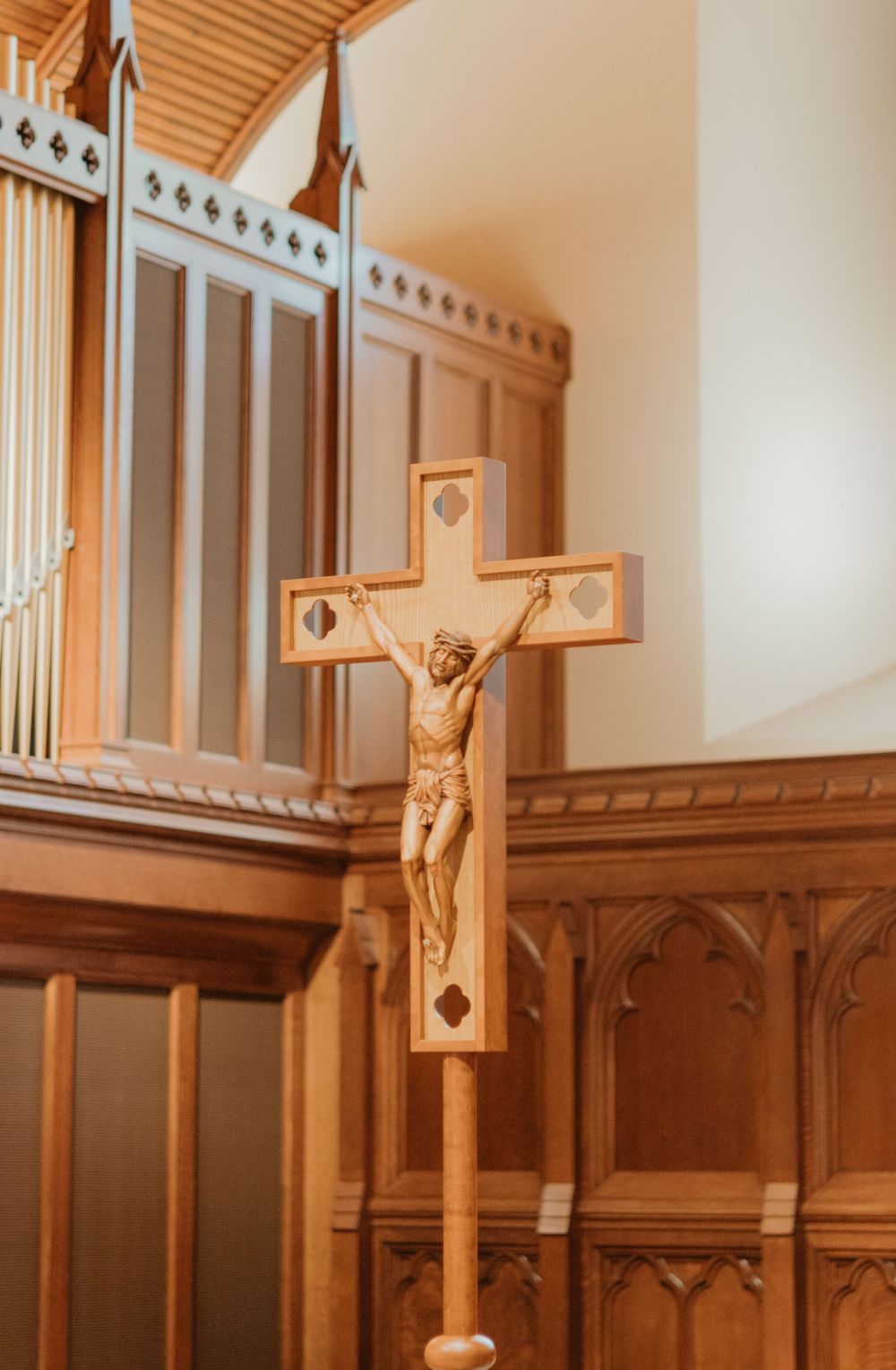 Wooden crucifix mounted on church wall with ornate architectural details.