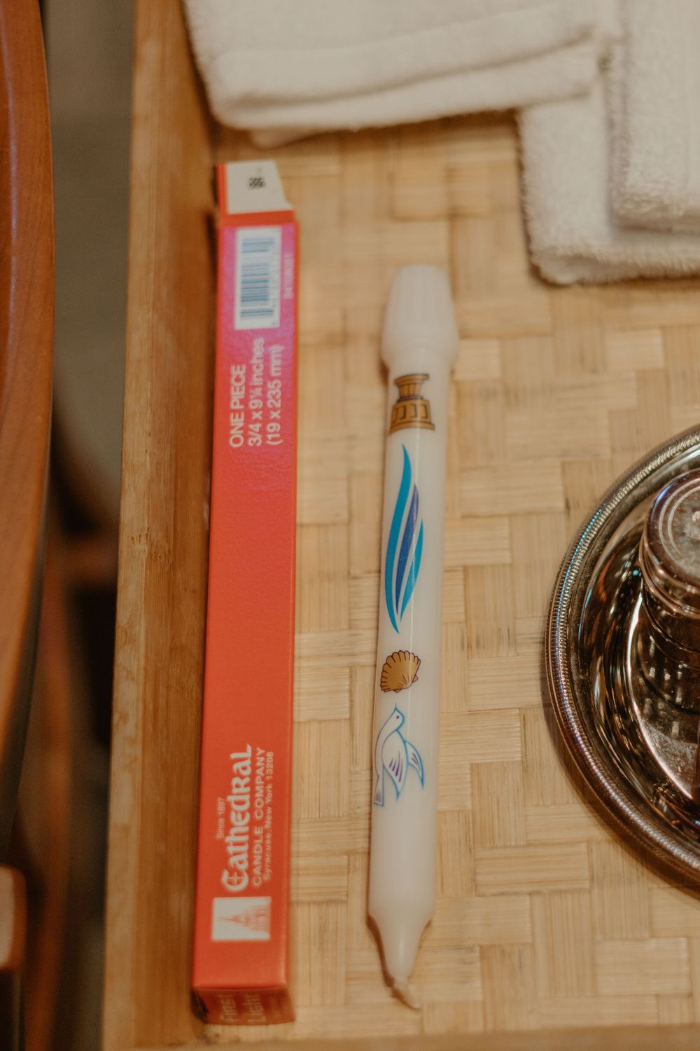 Pink box and decorated white pen sitting on a woven surface with other items.