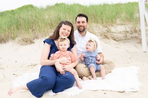 Light-filled beach session — family gathered close on white blanket, natural Cape Cod backdrop.