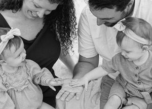 Black and white close-up of small child’s hands reaching playfully during family session.