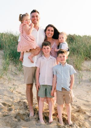 Golden hour family session — parents and children standing close together, beach grass softly glowing.