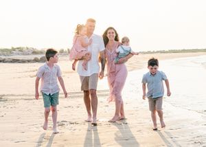 Joyful Cape Cod beach session — family laughing as they walk near shoreline at golden hour.