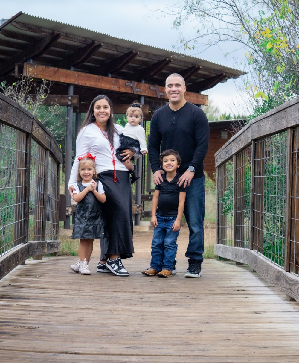 Family standing together on wooden bridge walkway.
