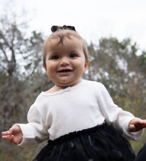 Sweet moment, baby looking at camera and smiling while sitting outside.