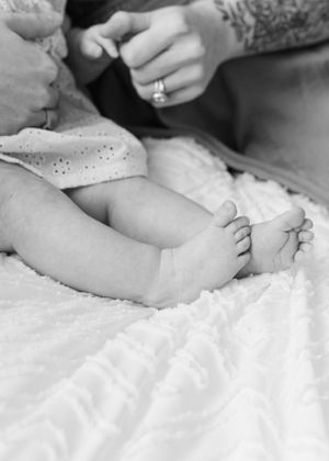 Black and white close-up of tiny newborn feet resting on soft white bedding.