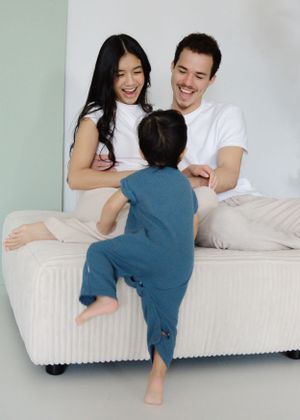 Light-filled family moment, playful interaction on white couch, full of connection.