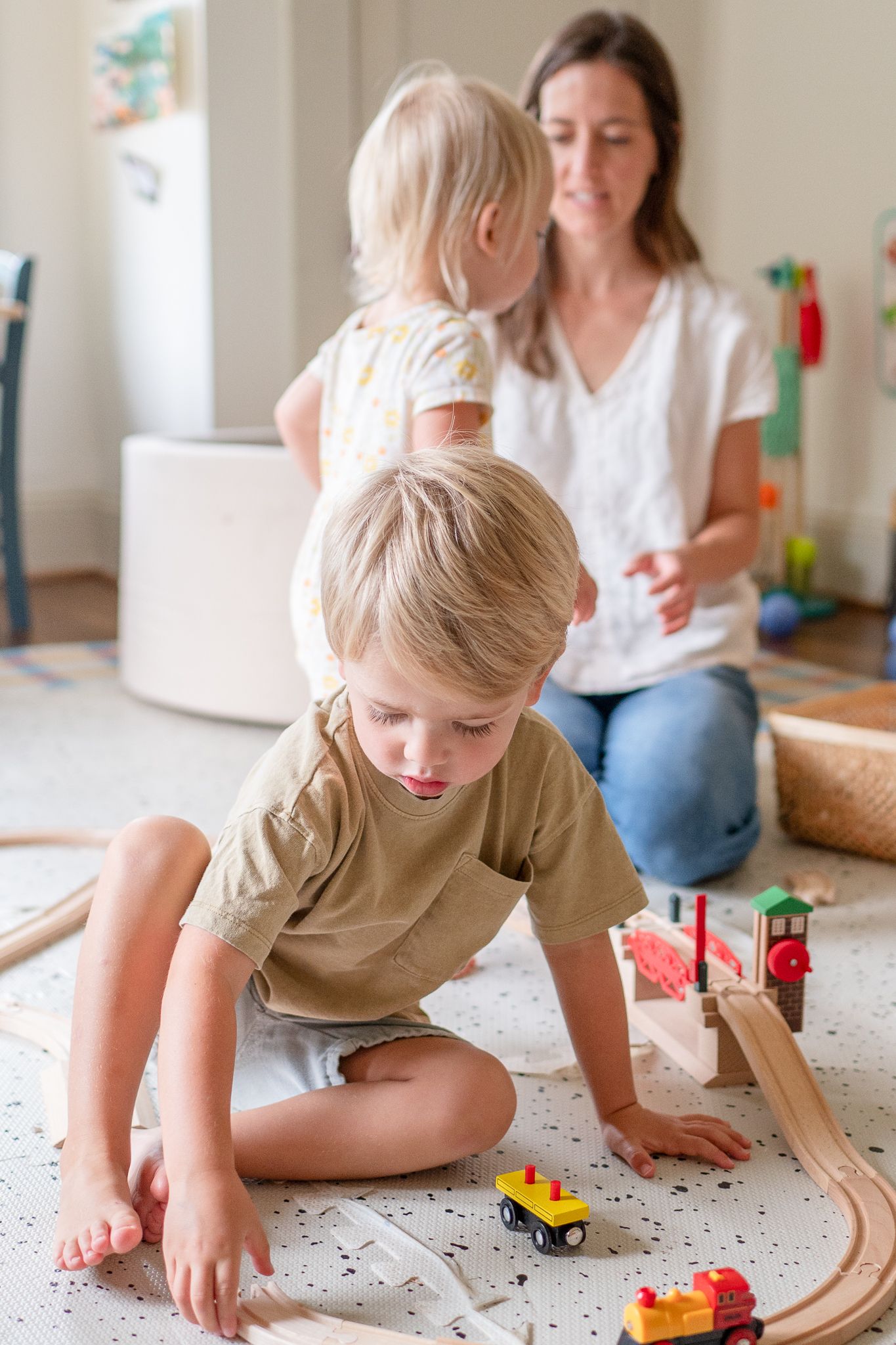 Little boy plays with his trains in his playroom during a family photo shoot at home.