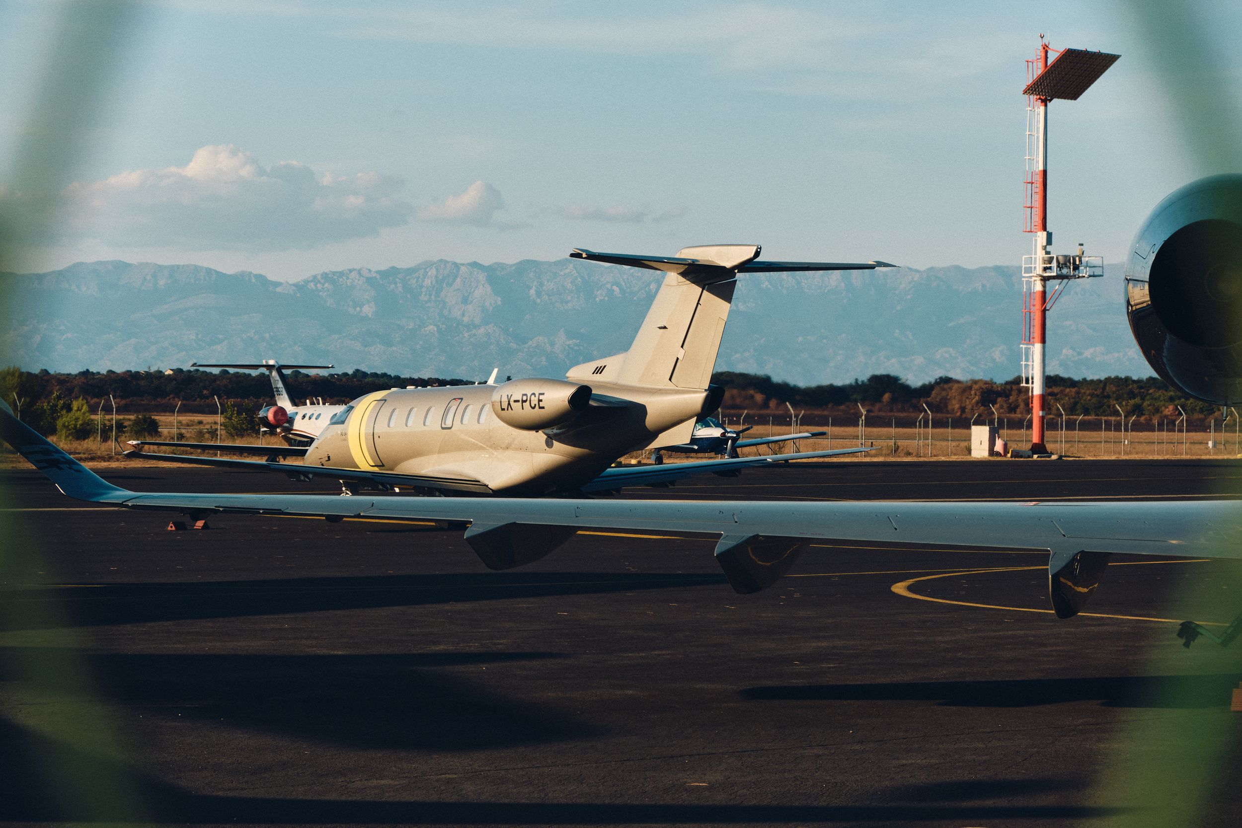 Small passenger aircraft parked on tarmac with mountains visible in the background.