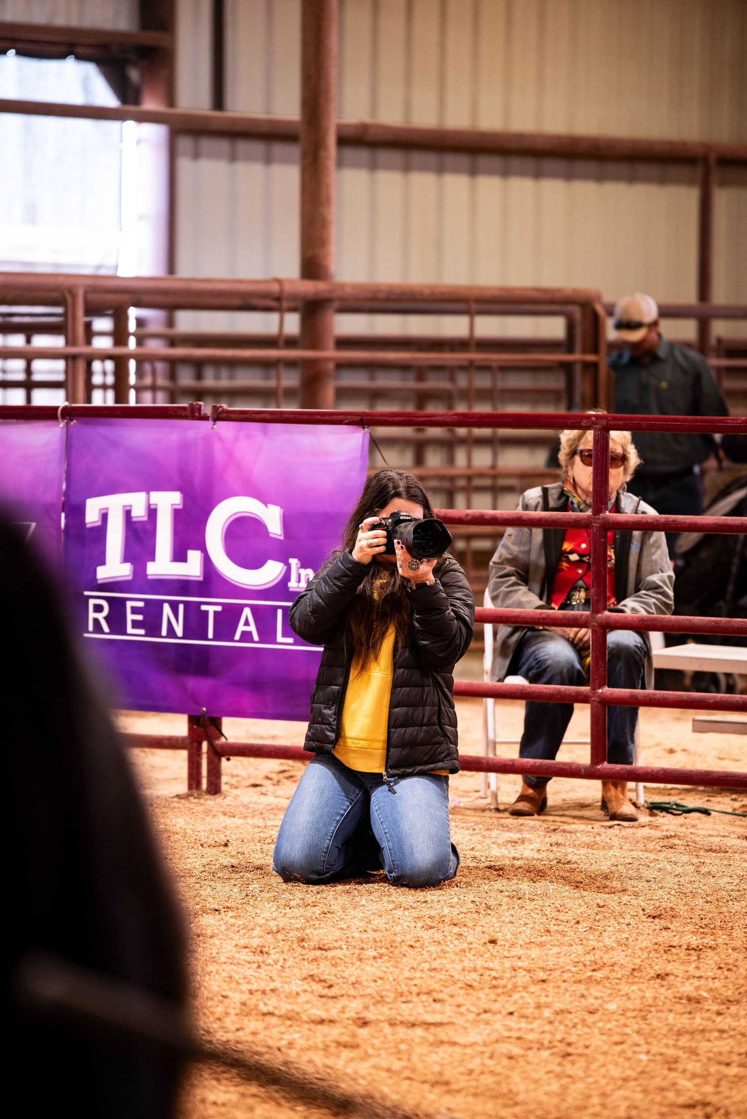 Photographers taking pictures in an indoor arena with purple TLC banner visible.
