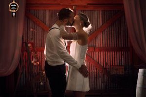 Bride and Groom embracing in a kiss inside barn at night backlit in front of red lit barn doors