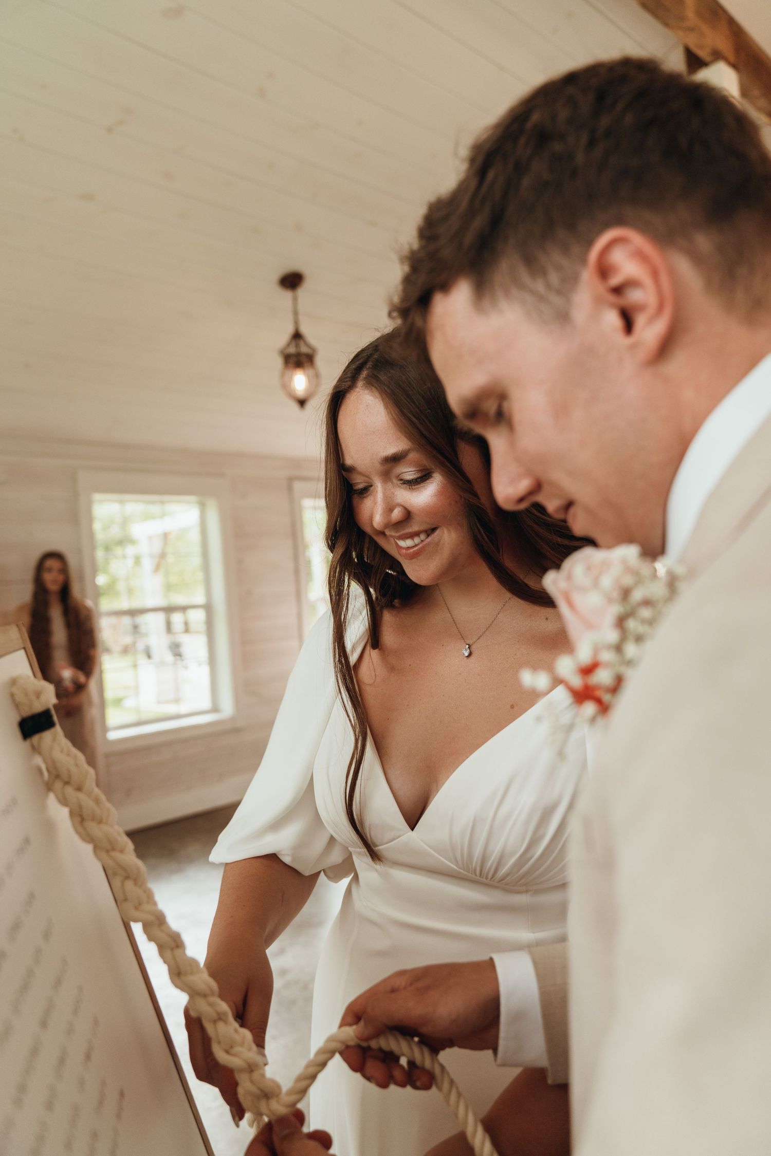 Bride and Groom braid three strands of rope during their unity ceremony at their wedding. Beautiful smiles and intimacy.