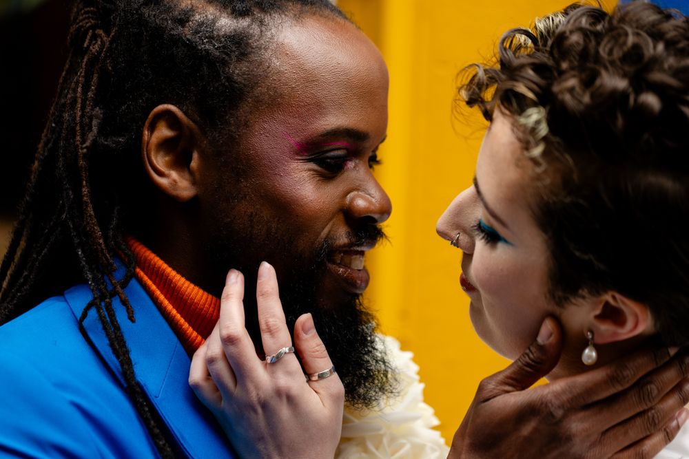 An intimate close-up portrait of a couple against a vibrant yellow background.