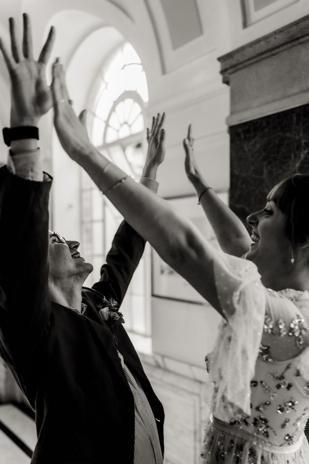 A sequence of black and white photos showing a person joyfully raising their arms in celebration at a formal event.
