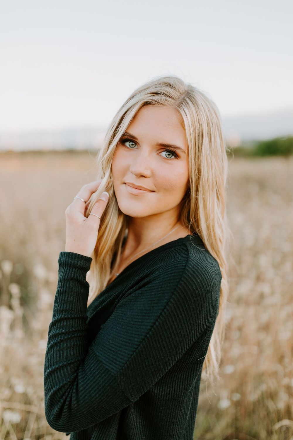 Portrait of someone in black sweater against a golden field background.