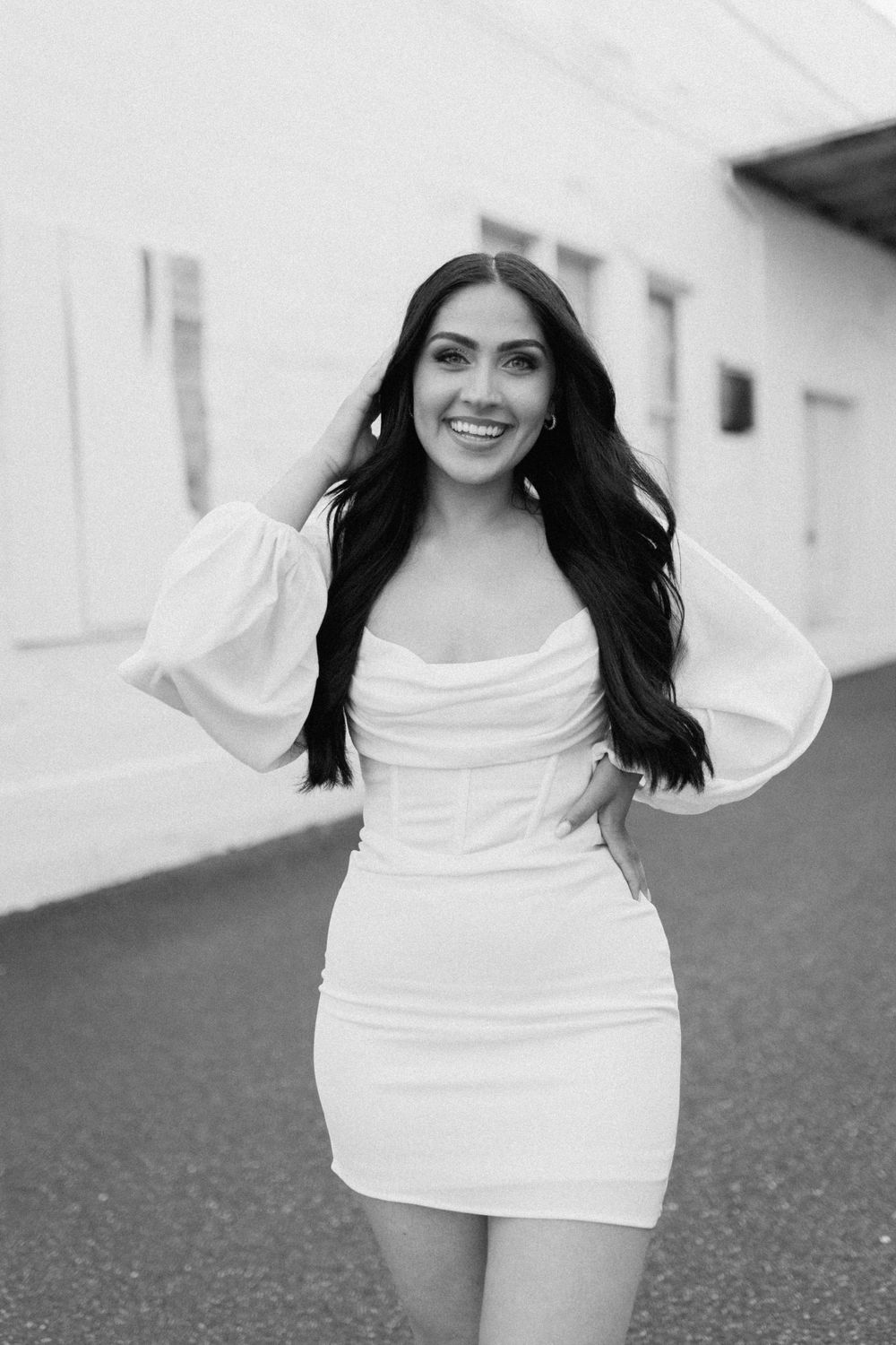 Black and white portrait of someone in a stylish white dress with puff sleeves.