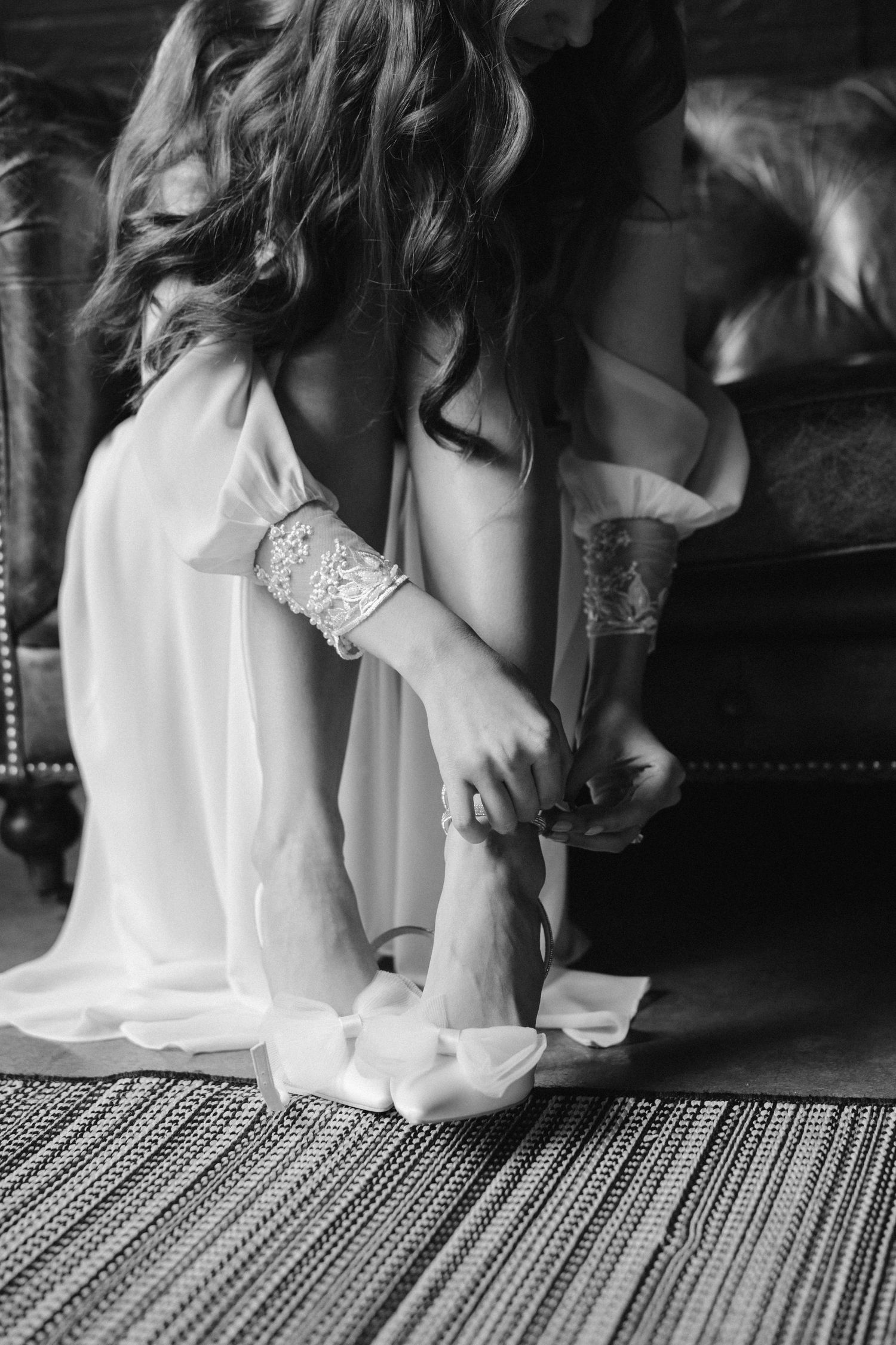Black and white detail shot of lace robe and feet on patterned rug.