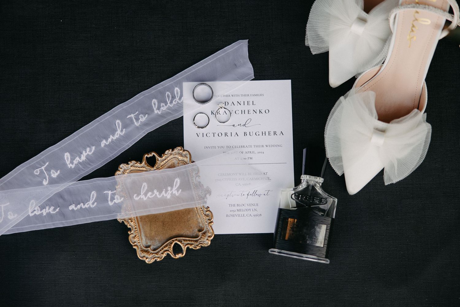 Wedding invitation suite with veil, shoes, and vintage jewelry box on dark surface.