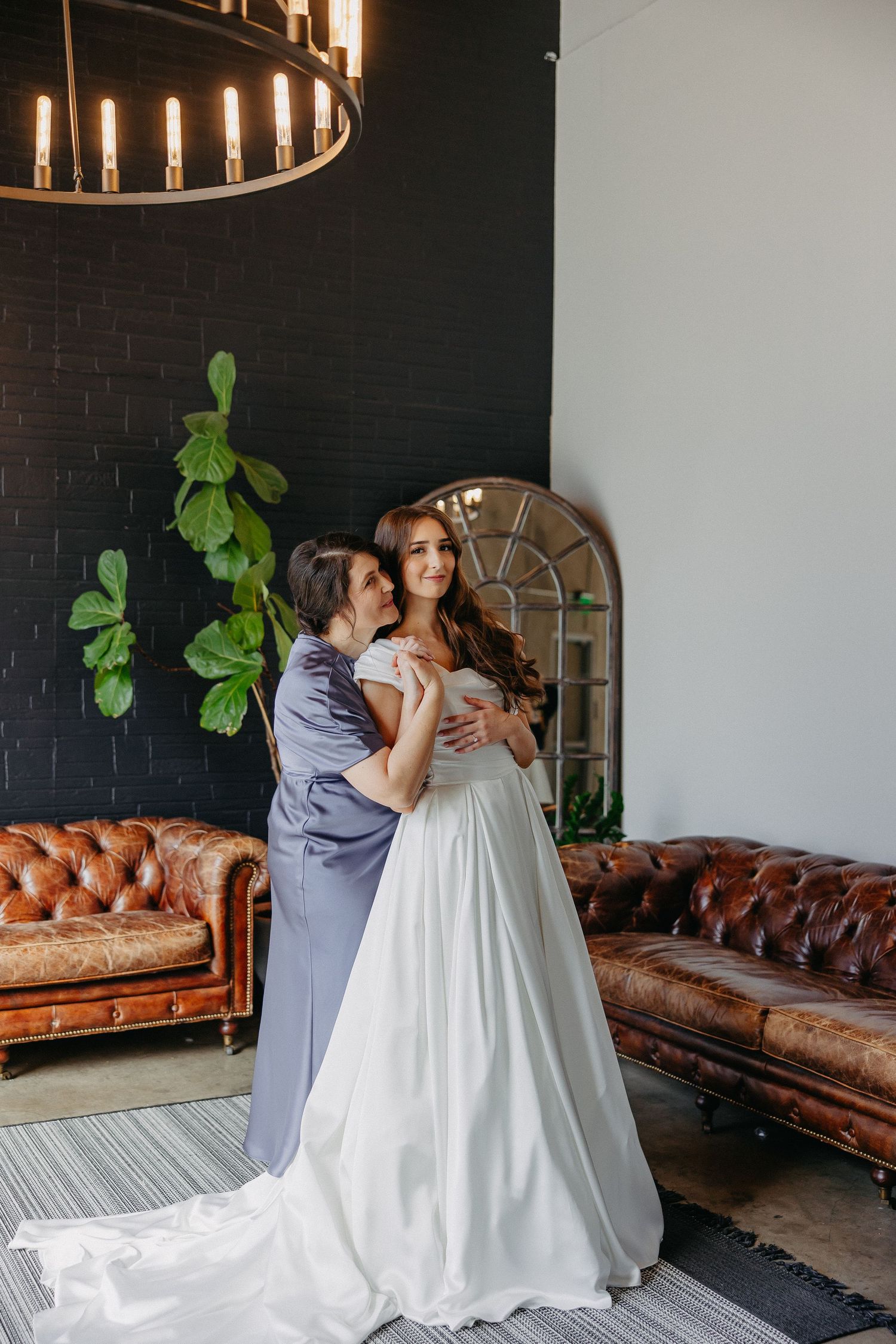 An elegant wedding photo showing preparations in a room with leather couches and black walls.