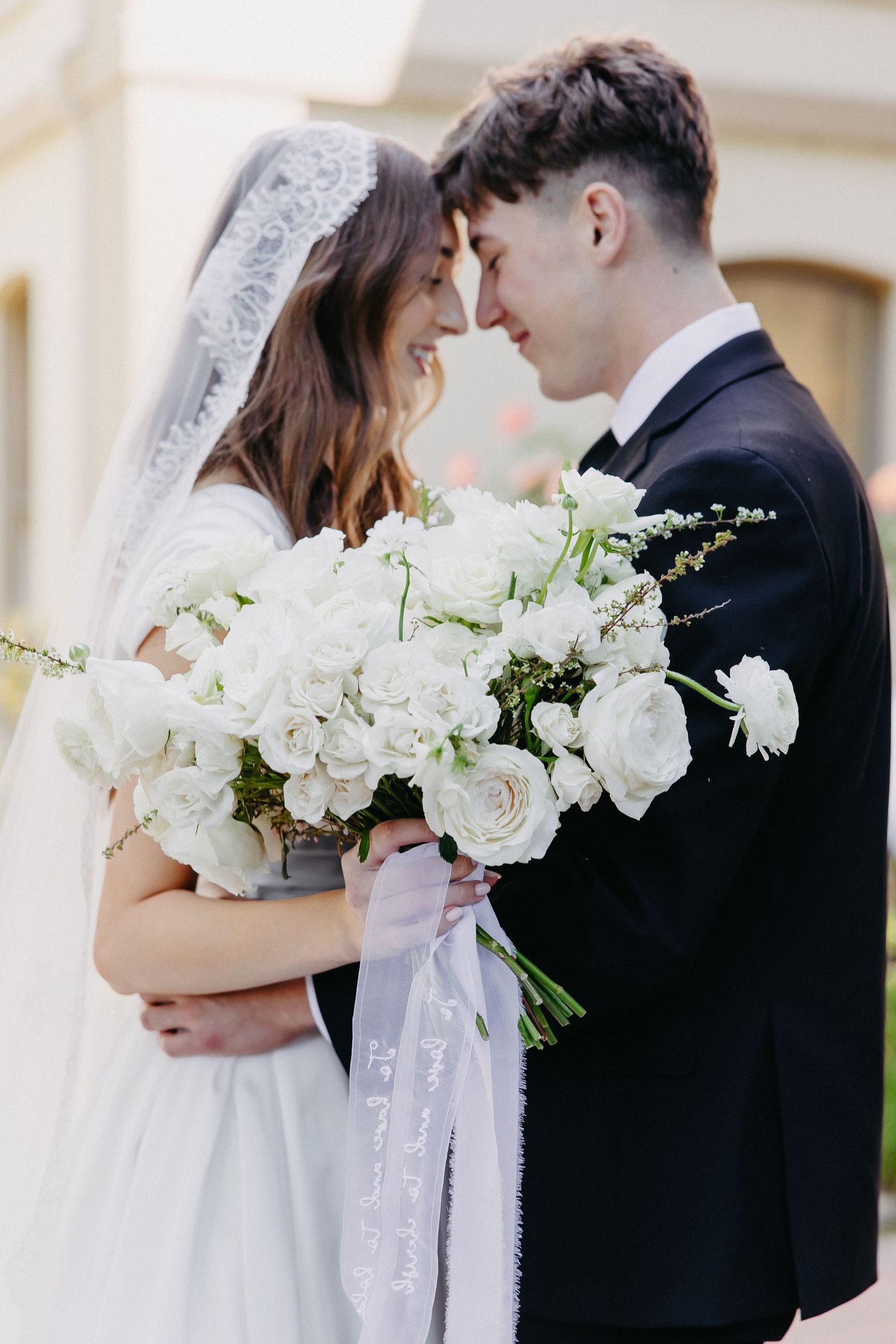 An intimate wedding portrait with a white rose bouquet and delicate veil details.