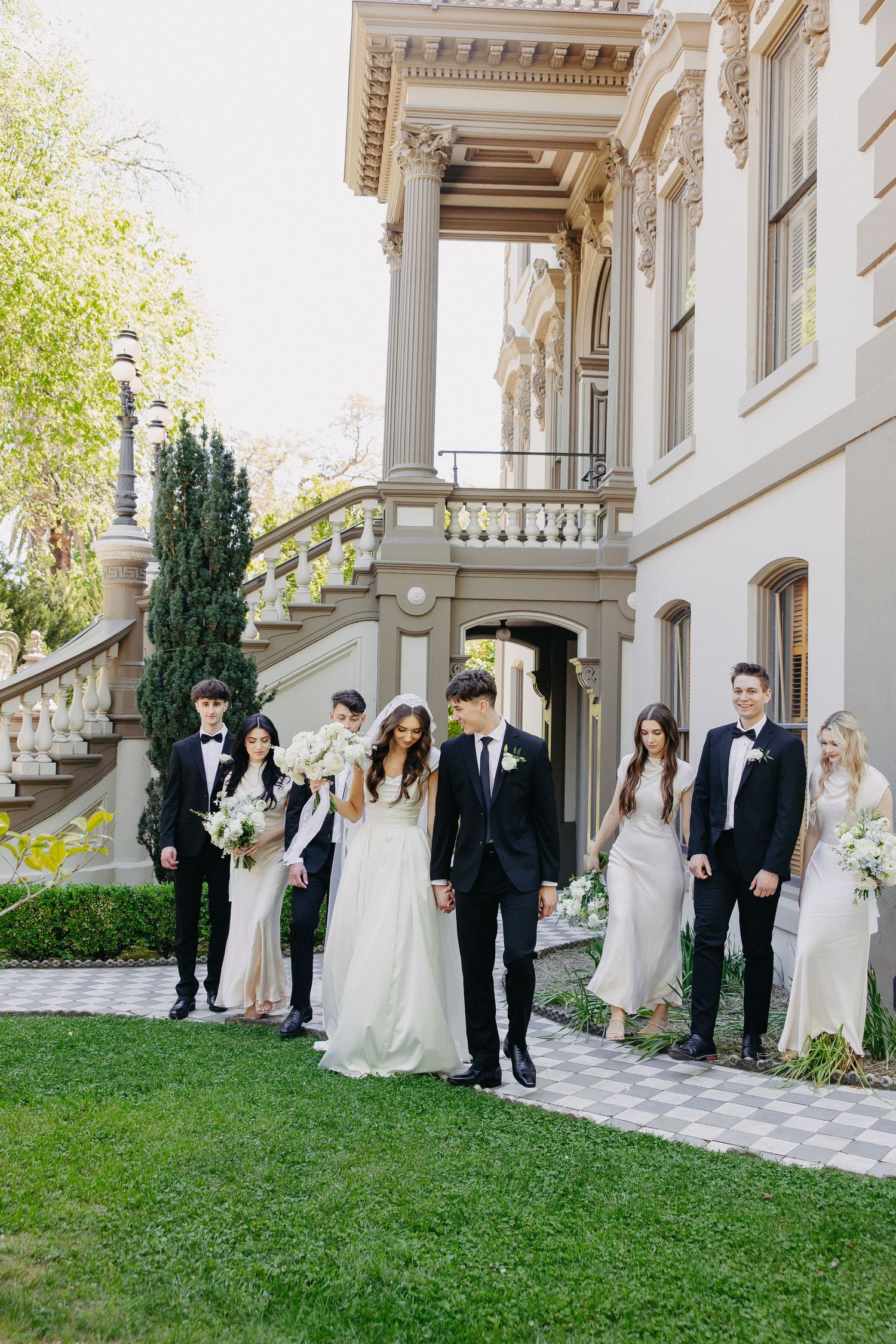 Wedding party members lined up against an elegant building with classical architecture.