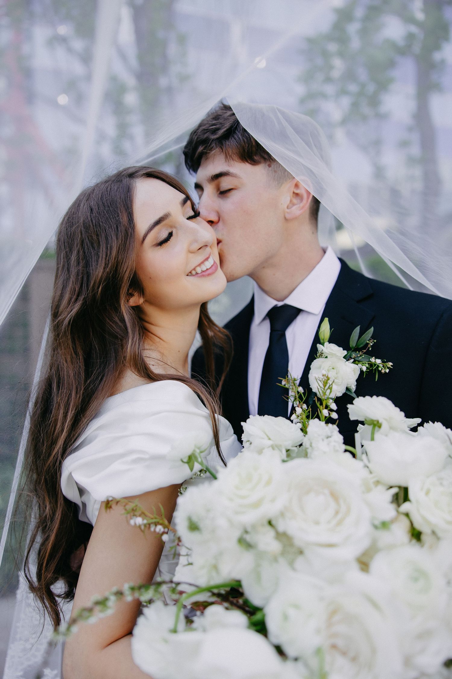 Tender wedding moment captured with white roses and dreamy lighting.