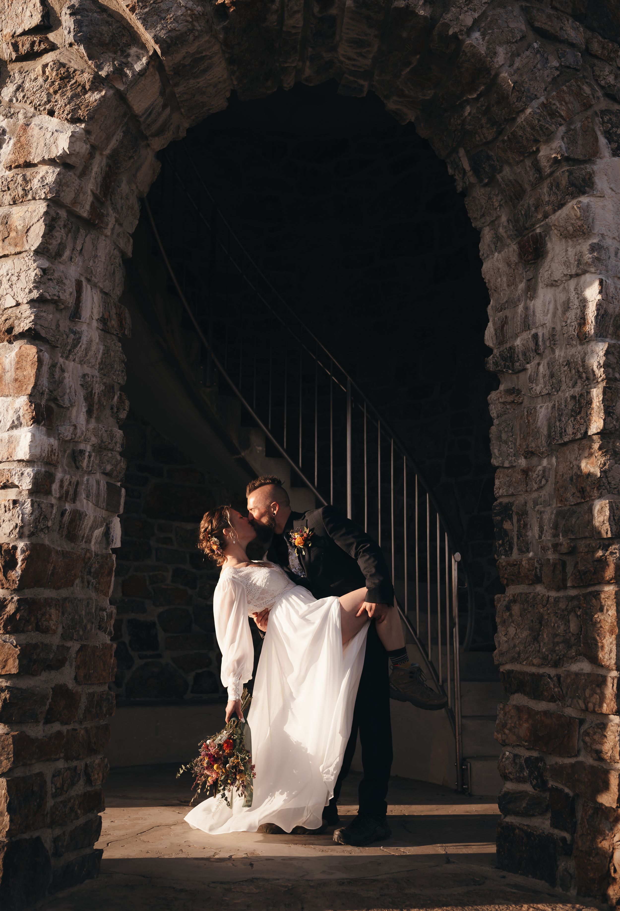 A romantic dip kiss between newlyweds in a lush garden setting.