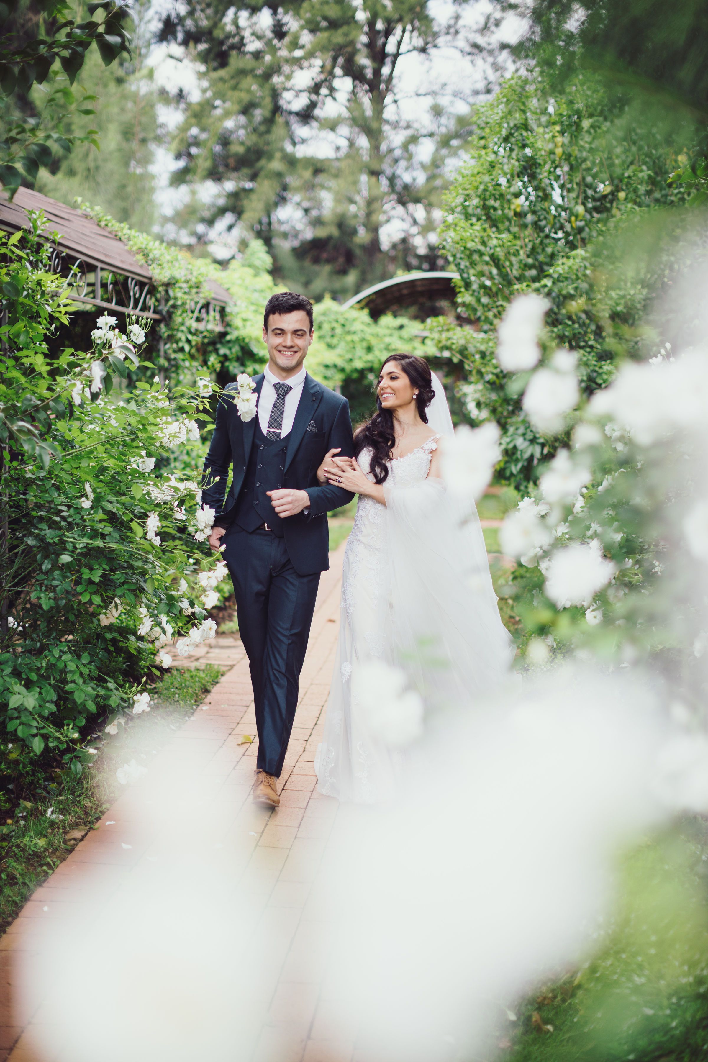 Bride and groom walking hand in hand through a rose garden after the ceremony