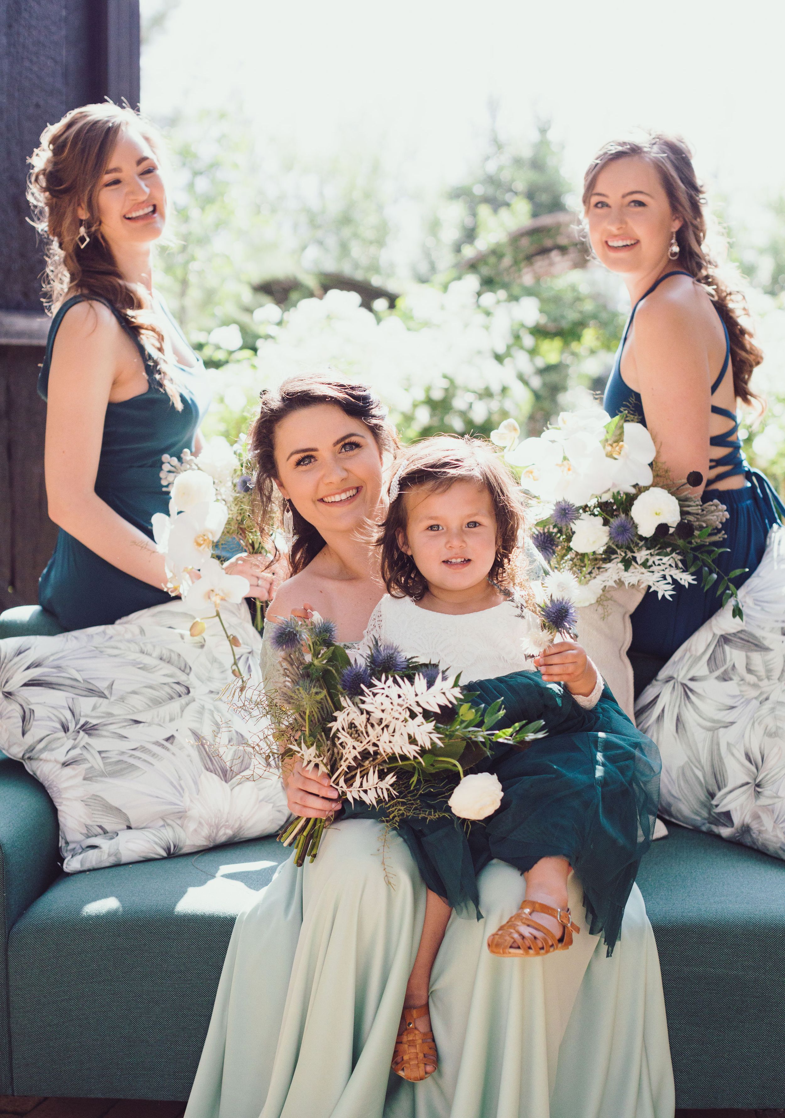 Bridesmaids and flower girl posing together in soft natural light before the ceremony