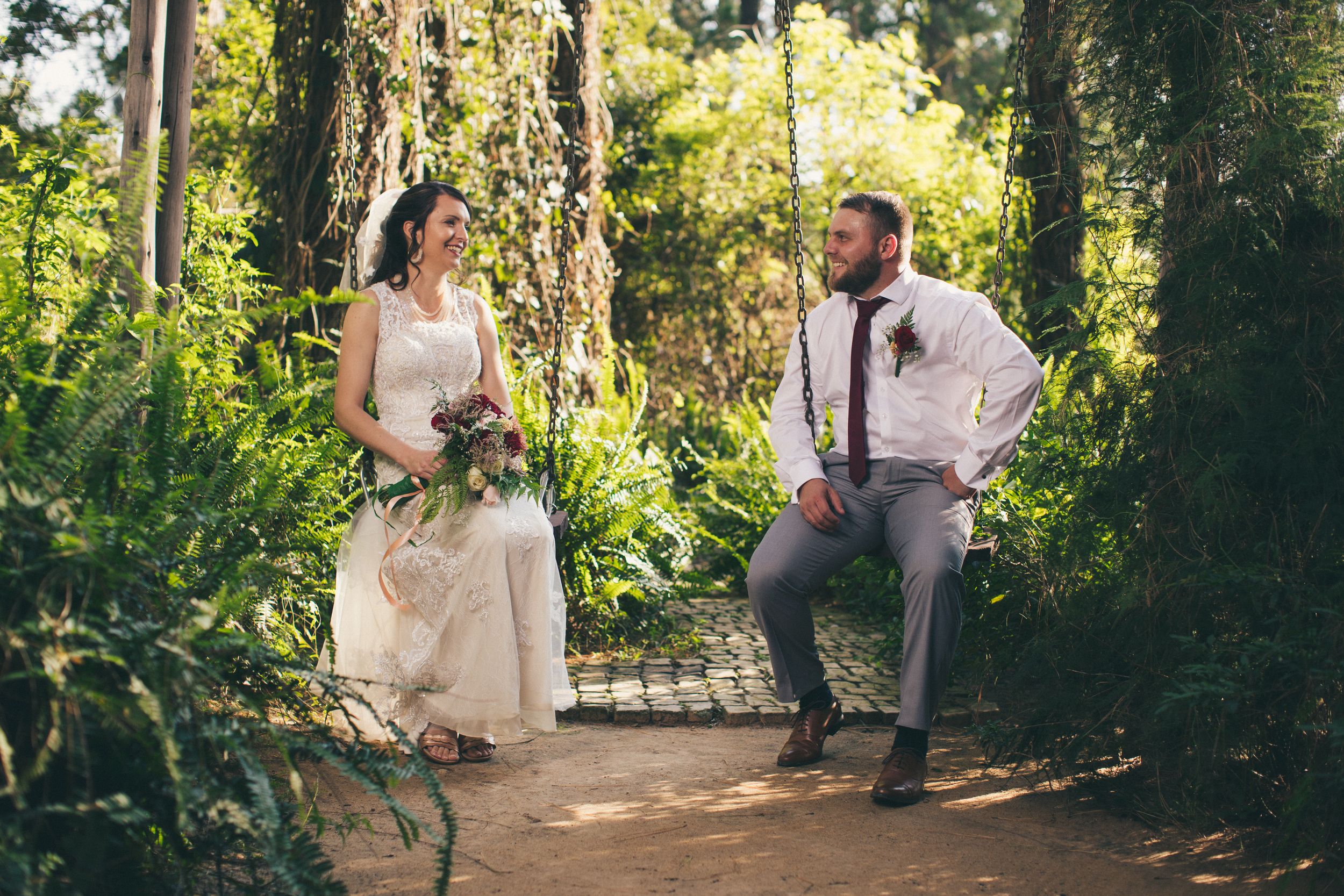 Bride and groom sitting on swings after the wedding in a beautiful garden