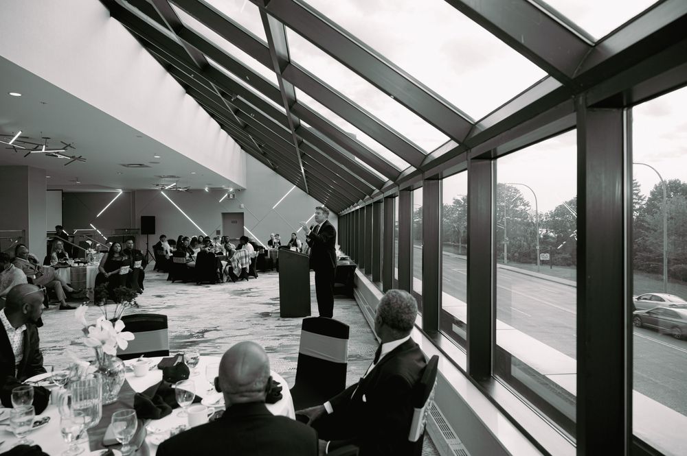 Interior view of a banquet room with large angled glass windows during a formal gathering.
