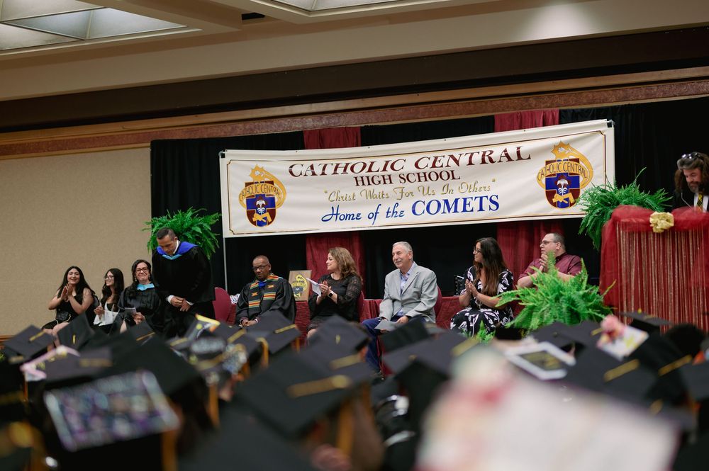 Catholic Central graduation ceremony with decorative stage and school banners.